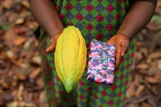 Dora Atiiga, Kakaobäuerin aus Ghana zeigt Kakaoschote und Schokolade. © Foto: Fairtrade, Nipah Dennis