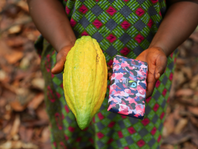 Dora Atiiga, Kakaobäuerin aus Ghana, zeigt Kakaoschote und Schokolade. © Foto: Fairtrade Nipah Dennis